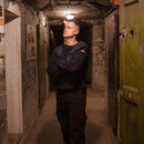 Man wearing original German army navy blue wool pullover with German flag patch in dimly lit corridor.