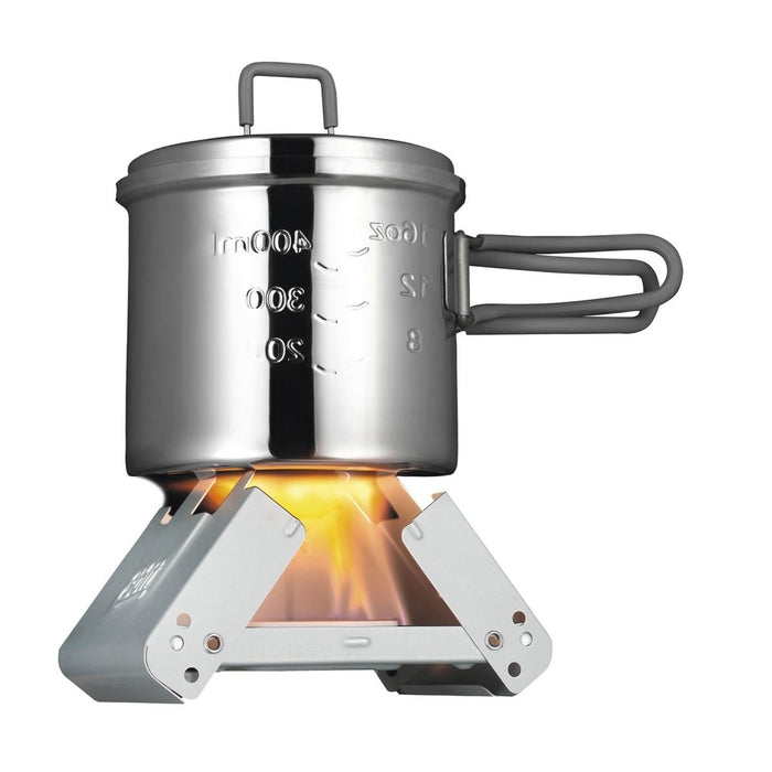 ESBIT kleiner faltbarer Taschenkocher mit Festbrennstoff, der einen Metalltopf mit Messmarkierungen auf einer Lagerfeuerflamme erhitzt