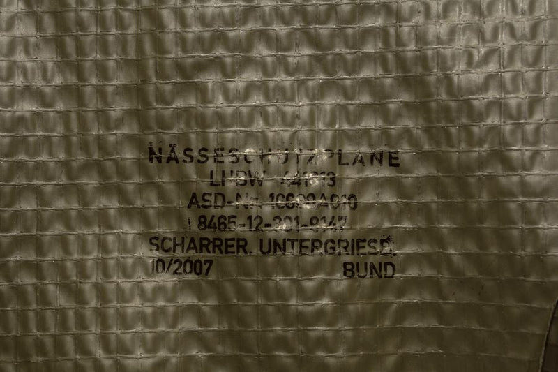 Close-up of genuine German Army olive drab waterproof groundsheet tarpaulin with military stenciled markings.