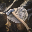 HULTAFORS Ekelund hunting axe with hickory handle and carbon steel head resting on a tree stump outdoors.
