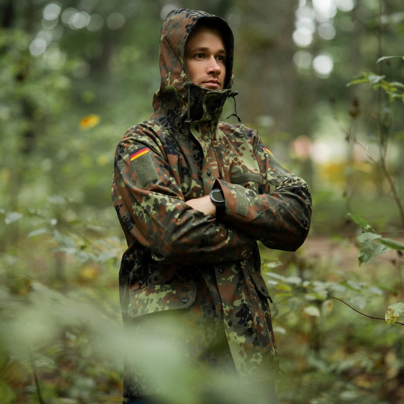 Man wearing Mil-Tec German army waterproof GoreTex Flecktarn camo jacket standing in forest