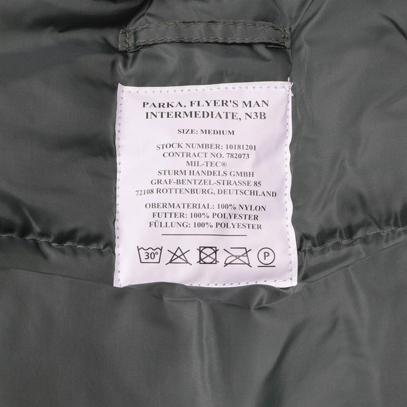 Close-up of MIL-TEC N3B aviator parka label showing material and care instructions on olive fabric background