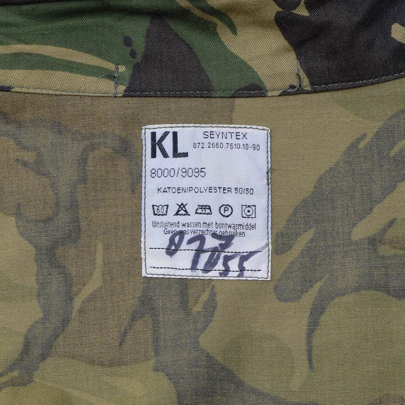 Close-up of a Dutch army M65 waterproof parka label showing fabric and care instructions on camouflage material