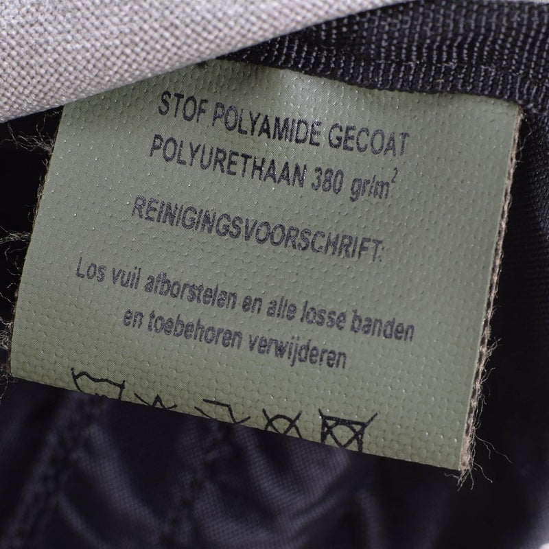 Close-up of a care label inside the Dutch Army Woodland Daypack showing material and cleaning instructions.