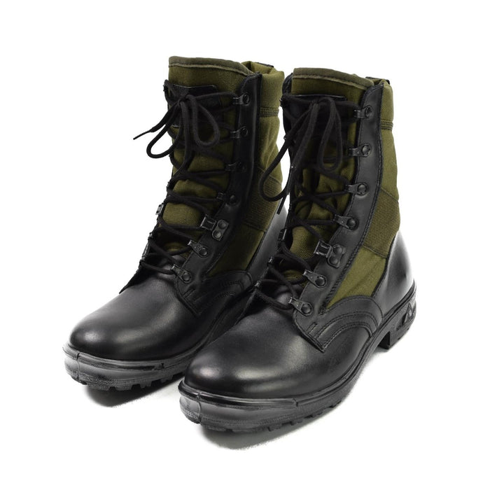 Paar schwarze und olivgrüne Tropenstiefel der Bundeswehr mit Schnürsenkeln und seitlichen Reißverschlüssen auf weißem Hintergrund