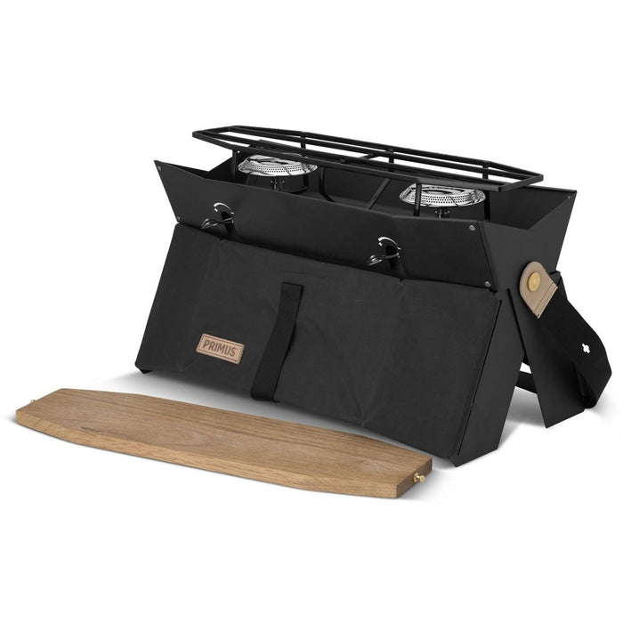 Kompakter Primus Onja Campingkocher mit zwei Brennern, faltbarem Design und Holz-Windschutzscheibe zum Kochen im Freien.