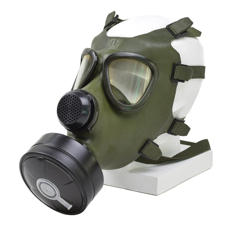 Vintage Romanian M74 full face olive green gas mask with black filter and adjustable straps on white display mannequin