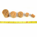 Set of five tapered vintage German cork plugs for sealing bottles and containers, shown next to measuring tape.